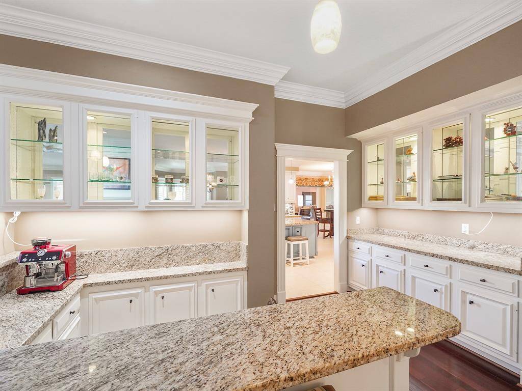 The wet bar and a well-appointed butler's pantry conveniently located adjacent to the formal dining and living room. This thoughtfully designed space offers ample storage solutions, including a beautifully crafted china cabinet, ensuring that your dining essentials are both accessible and aesthetically pleasing. The stunning granite countertops provide a luxurious touch, while the illuminated displays enhance the ambiance