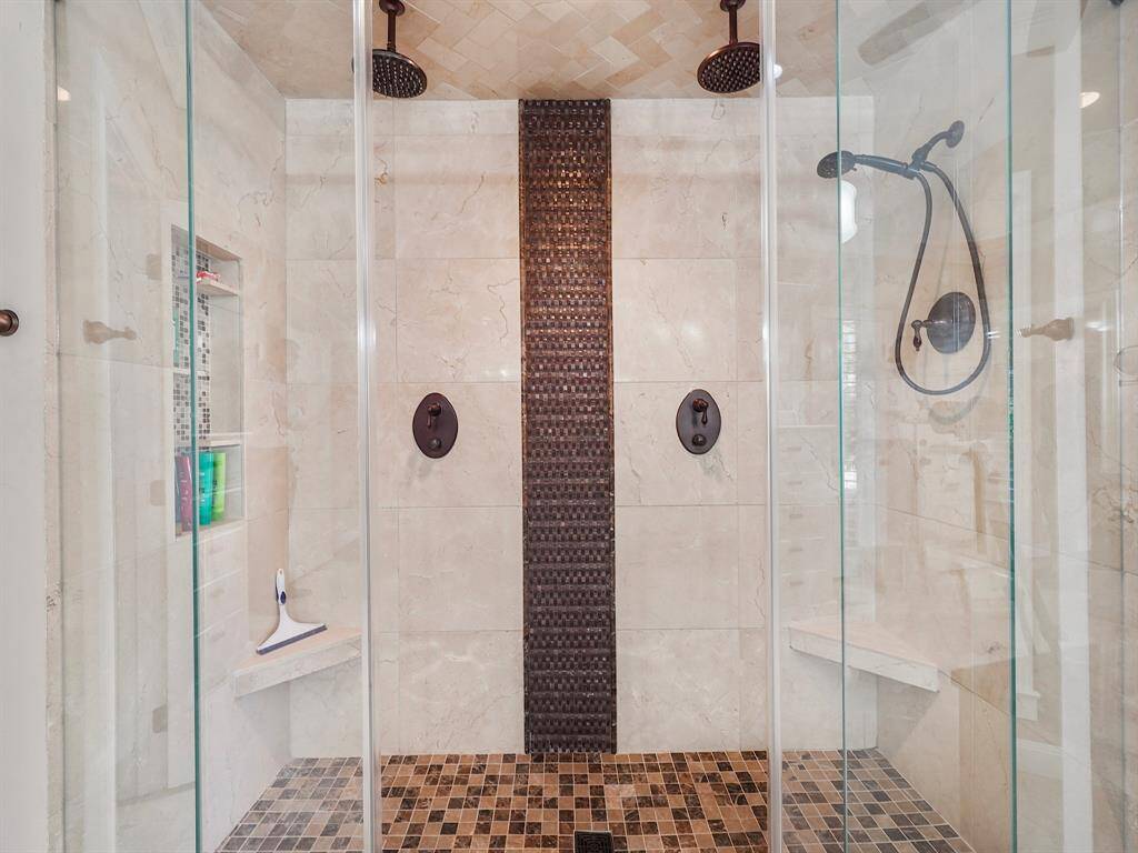 The oversized walk-in shower is a standout feature, boasting dual rain heads and a handheld shower head for a truly indulgent experience.