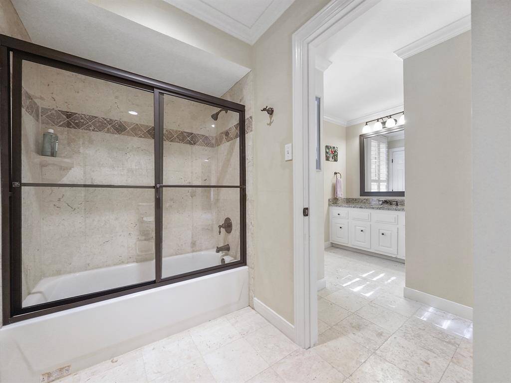 Experience luxury with a fully tiled tub shower combo featuring a sleek sliding glass door for a modern touch. This is located off of the secondary bedroom #3 and the game room.