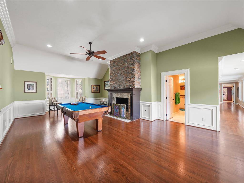 Discover a spacious game room featuring a stunning stone fireplace, charming bay window, soaring high ceilings, elegant crown molding, and a convenient wet bar—perfect for entertaining!