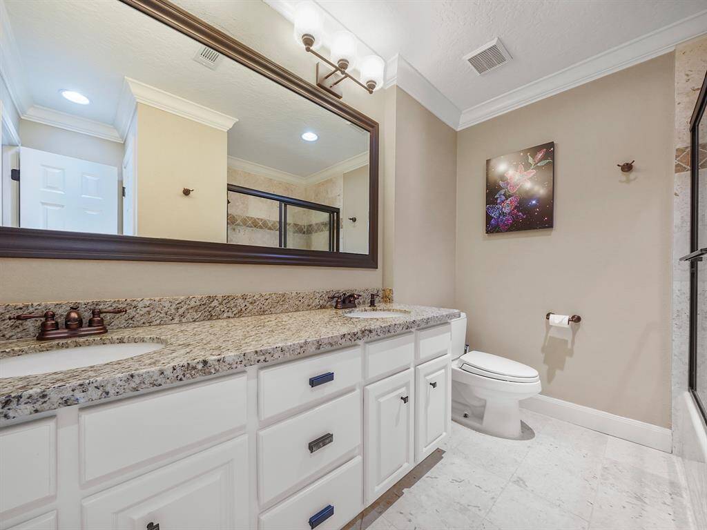 Experience luxury in the beautifully designed bathroom of this apartment-style suite. Featuring dual sinks with elegant granite countertops, this space combines functionality with modern aesthetics. The stunning crown molding adds a touch of sophistication, while the convenient sliding glass doors lead to a relaxing tub/shower combo.