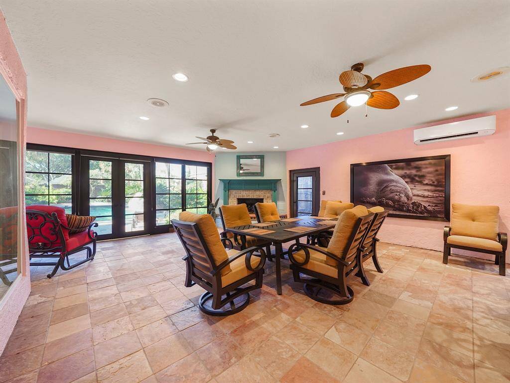 Experience year-round outdoor living in this beautifully enclosed outdoor kitchen and patio, complete with a cozy fireplace for ultimate comfort! This climate controlled space is equipped with anodized aluminum French doors by Sunspace that allows views of the pool!