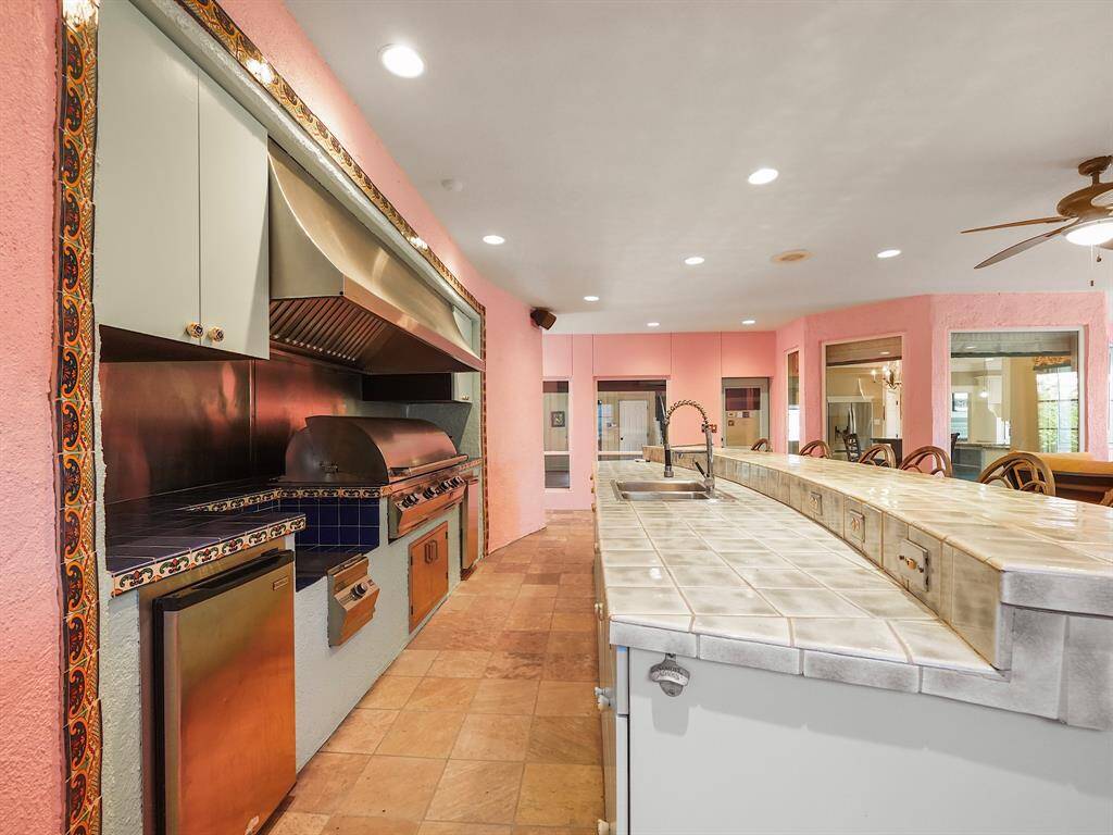 Experience outdoor living at its finest with a stunning kitchen featuring a Fire Magic commercial-grade grill, pot burner, and vent hood. Enjoy the convenience of a refrigerator, ice maker, full sink, and ample storage, all overlooking a sparkling pool.