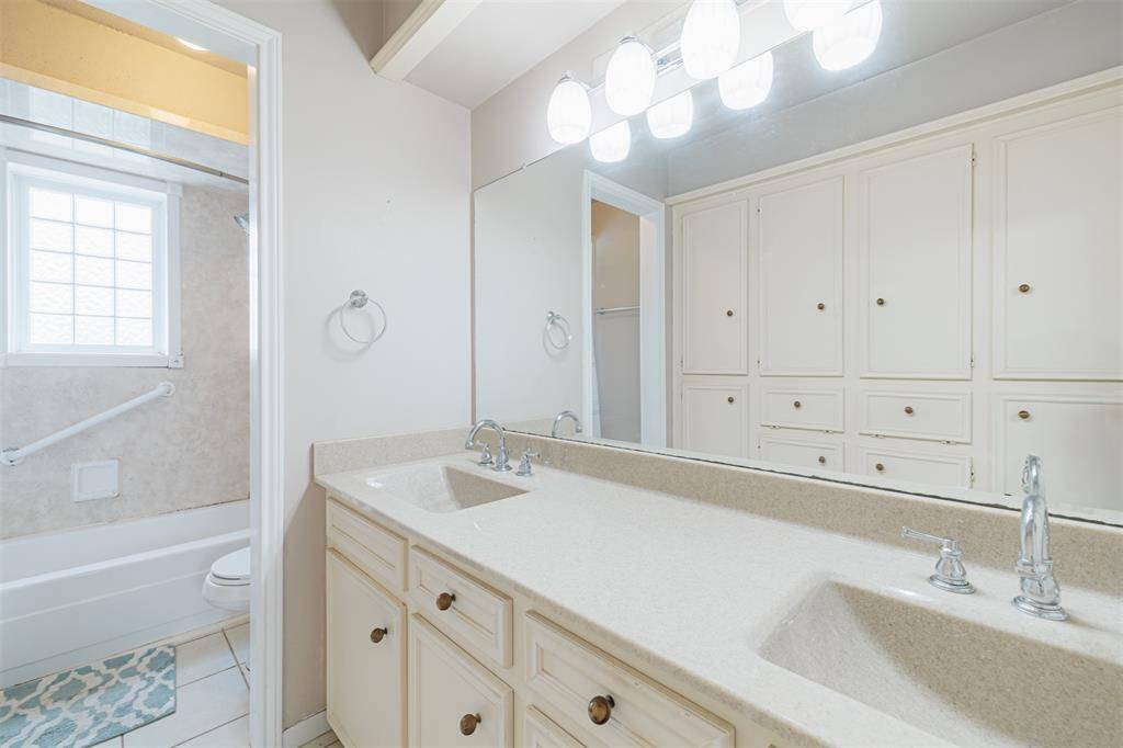 Secondary bath with tub/shower combo and double sinks.  Opposite of the sink area is a wall of built-in storage perfect for towels, toiletries, and linens.