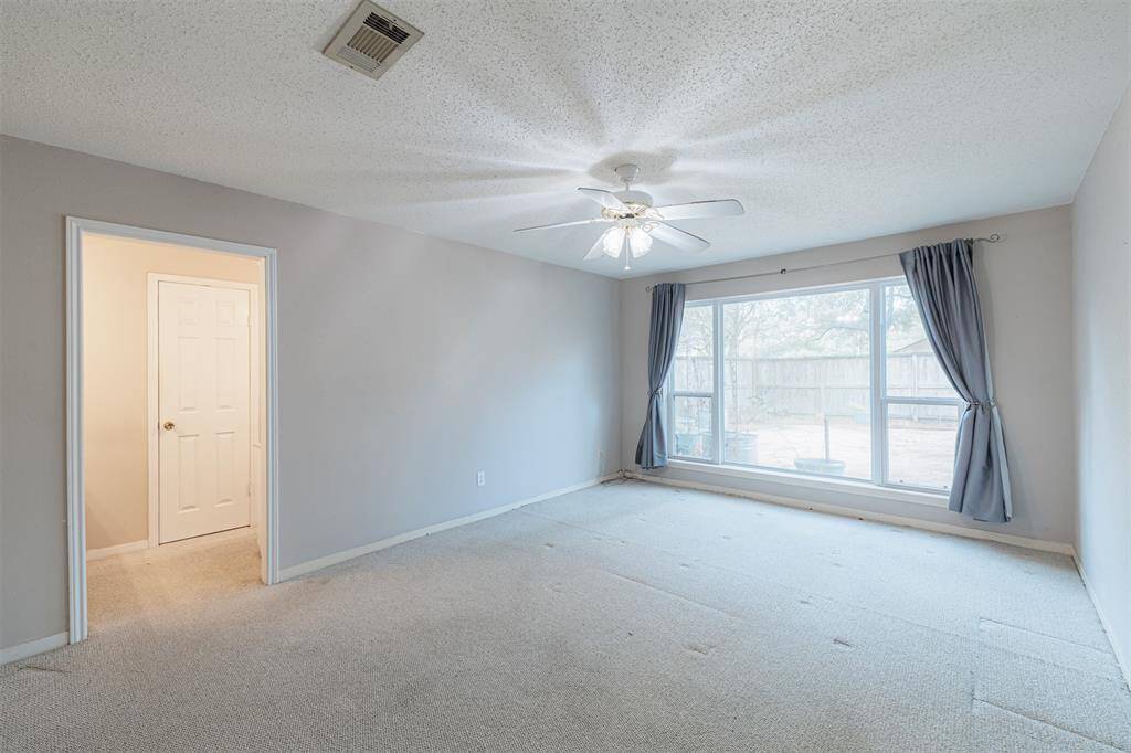 Spacious primary bedroom with floor to ceiling window.  Natural light warms the space.