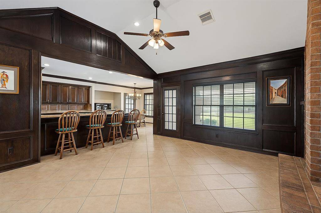 A warm and inviting family room showcases rich wood accents, a cozy fireplace, and a spacious built-in bar with seating for five—ideal for casual entertaining and relaxed evenings.