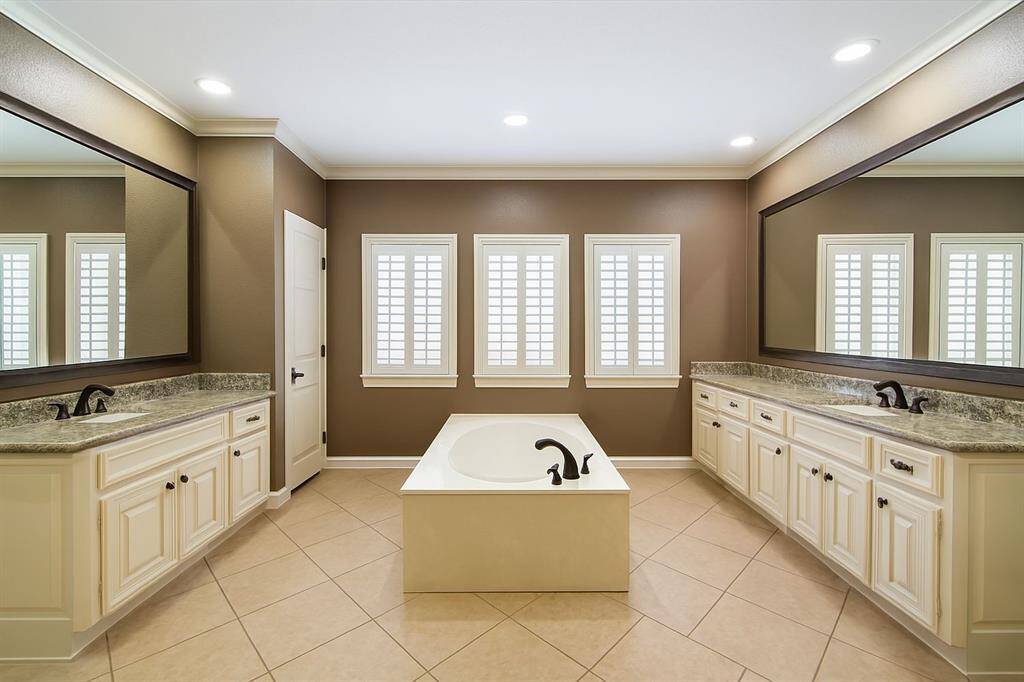 This beautifully updated bathroom boasts a clean, modern aesthetic with crisp white cabinetry, a stunning granite countertop, and a large framed mirror. The sleek tile flooring and glass-enclosed shower create a spa-like retreat—perfect for starting or ending your day in comfort and style.