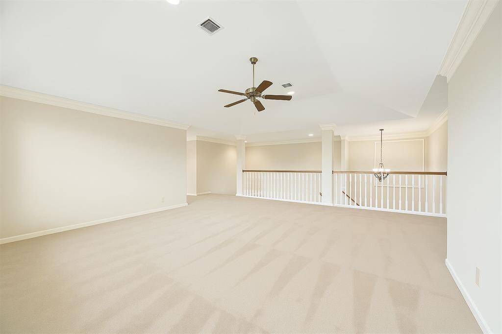 Endless possibilities await in this expansive upstairs loft, ideal as a game room, home theater, or second living area. Neutral tones, plush carpet, and elegant crown molding create a comfortable yet refined atmosphere with ample room to stretch out and unwind or entertain guests.