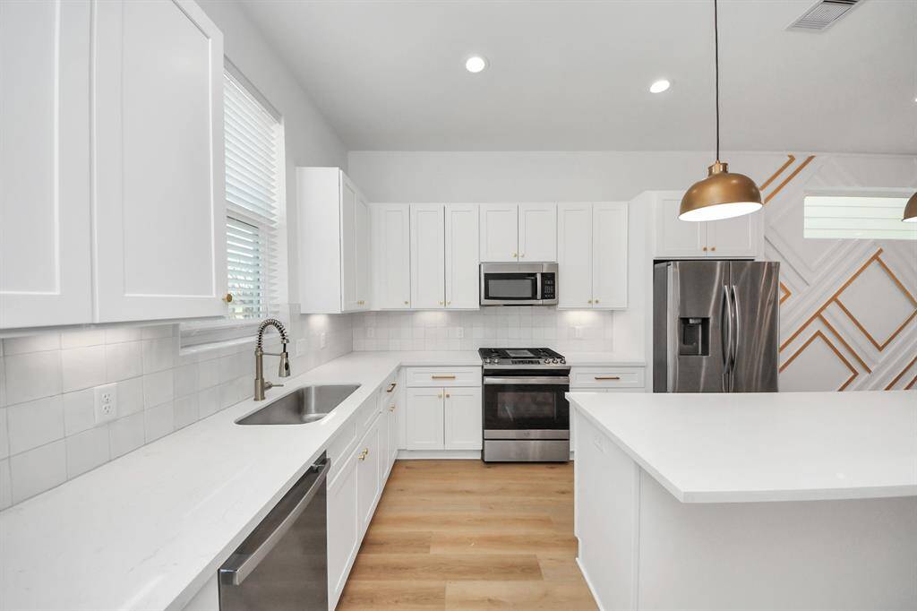 This kitchen just feels so bright and airy. Lots of natural light flowing in throughout the day from the large window above the sink. Light cabinets with brass/gold accent hardware, ample storage and counter space, a large kitchen island with stylish pendants - perfect for cooking, hosting dinners, or entertaining.