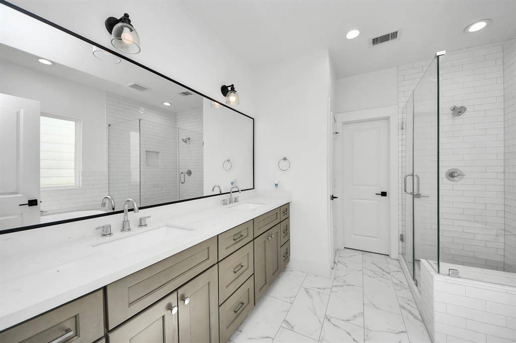 This primary bathroom is designed for a spa-like experience! Featuring an expensive vanity area with double sinks, glass-enclosed shower, and a free standing tub.