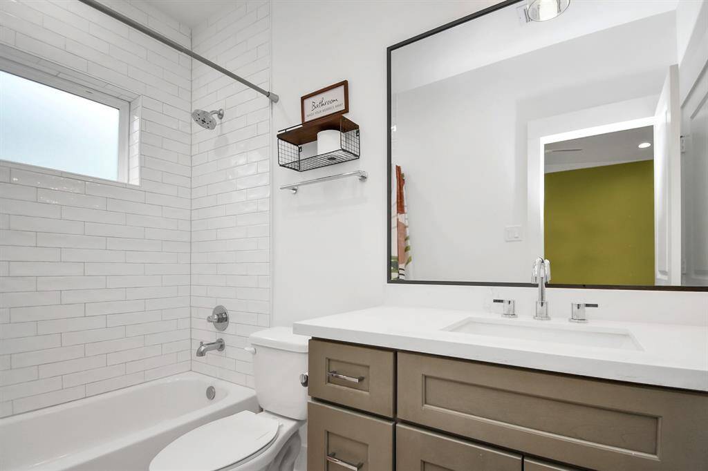 The en-suite bathroom on the first floor features neutral-toned cabinets, subway tiles, and a dark-framed mirror for color contrast.