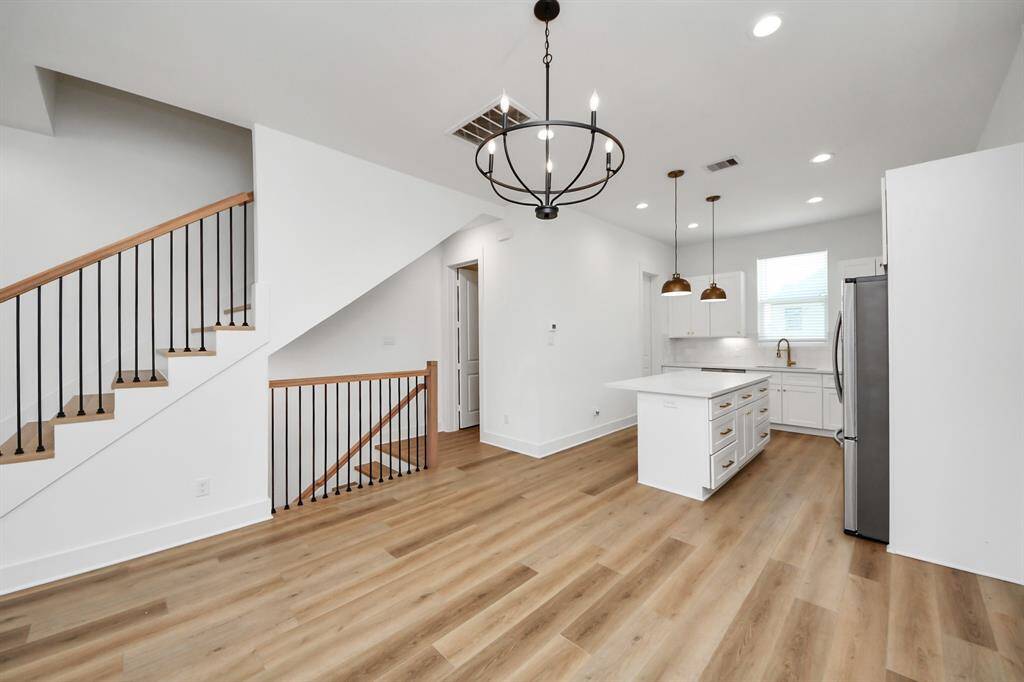 Dine in style in this dining/kitchen combo. Featuring stylish light fixtures, high ceiling, and vinyl flooring. The half bath is located just right off the corner for convenience.