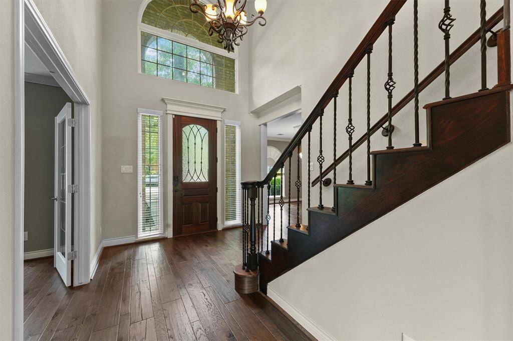 Two story entry with wood floors and stairs with wrought iron spindles.