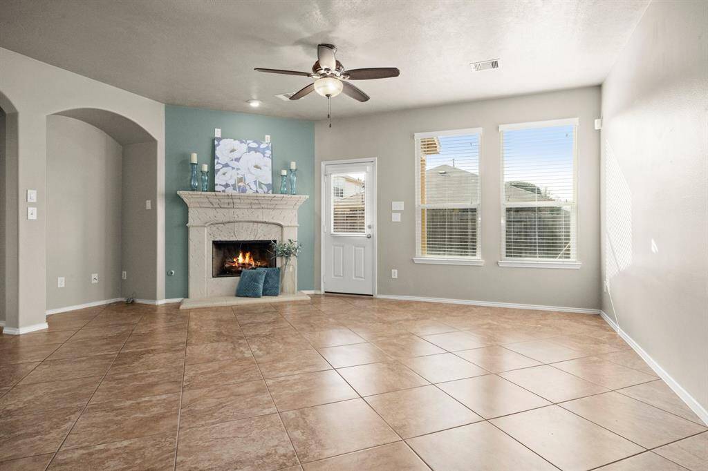 Sun-filled family room with large windows, gas log fireplace, arched niche, tile floors and ceiling fan.