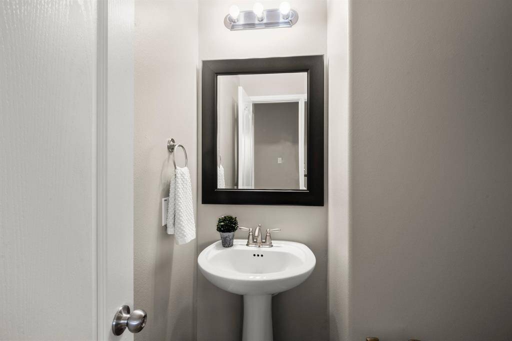 Powder room includes satin finished fixtures, framed mirror and elongated toilet.