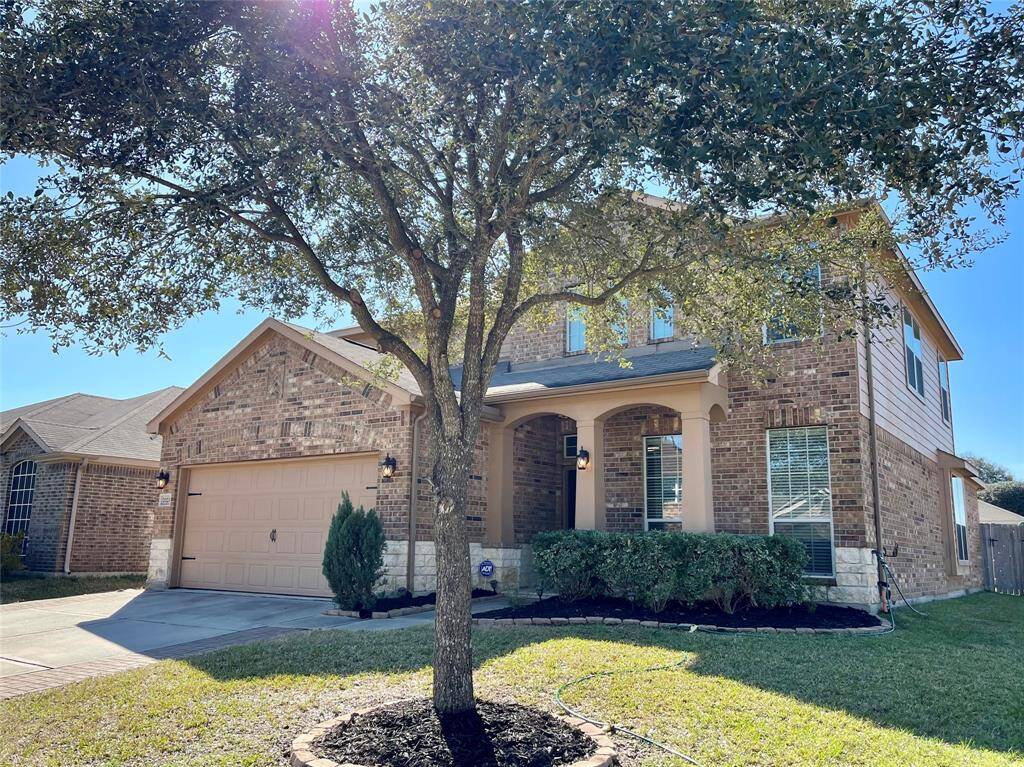 This handsome brick and stone elevation sits on a corner lot in Willow Falls, in the NW Houston suburb of Tomball Texas. Pavers line the driveway and a beautiful oak tree shades the house... thoughtfully placed and perfectly trimmed.