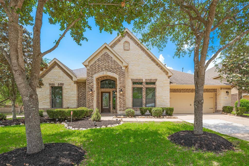 Elegant stone and brick elevation with arched entryway, beautiful landscaping- WELCOME HOME!