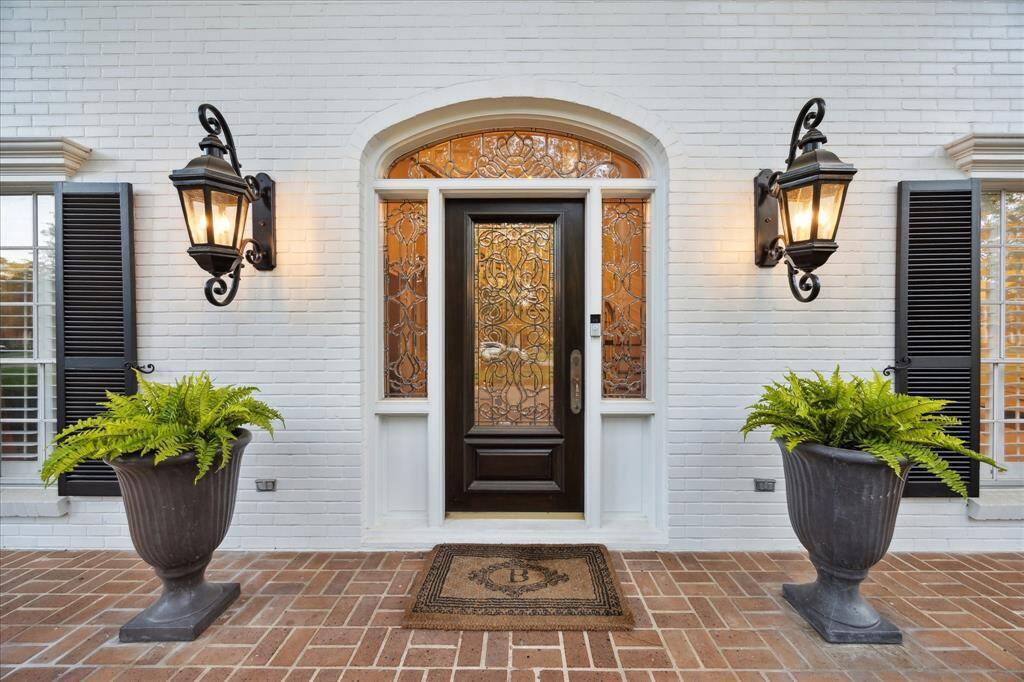 Gracious entry. Brick front porch with leaded glass door and side lights flanked by carriage lamps