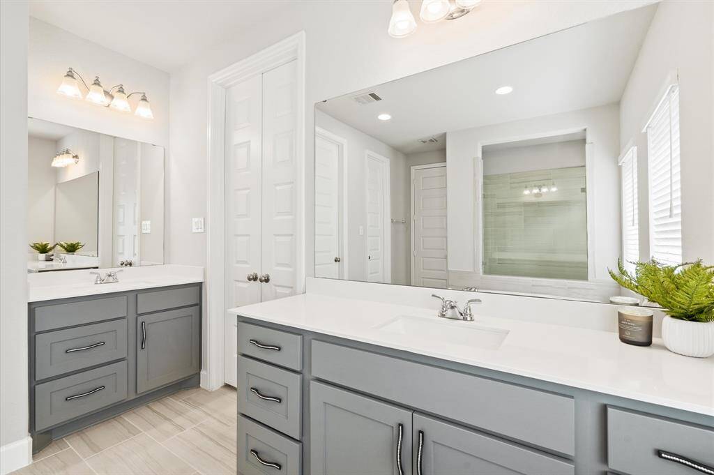Primary bathroom featuring a large walk-in shower, separate vanities, quartz countertops, custom hardware and elegant features.