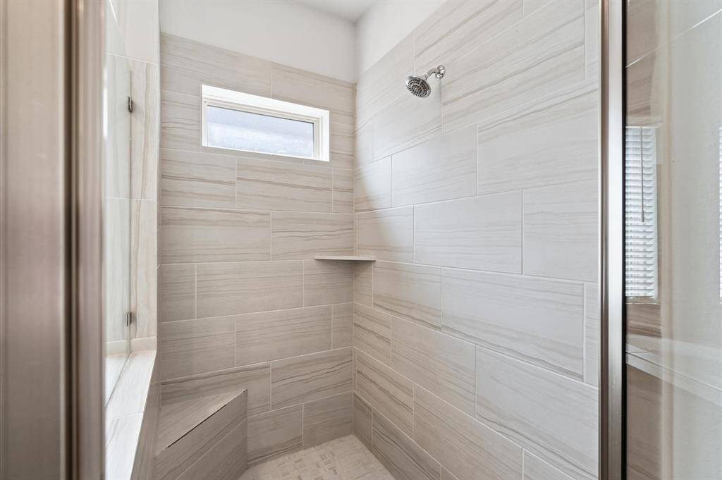 Spacious walk-in shower with bench and natural light.