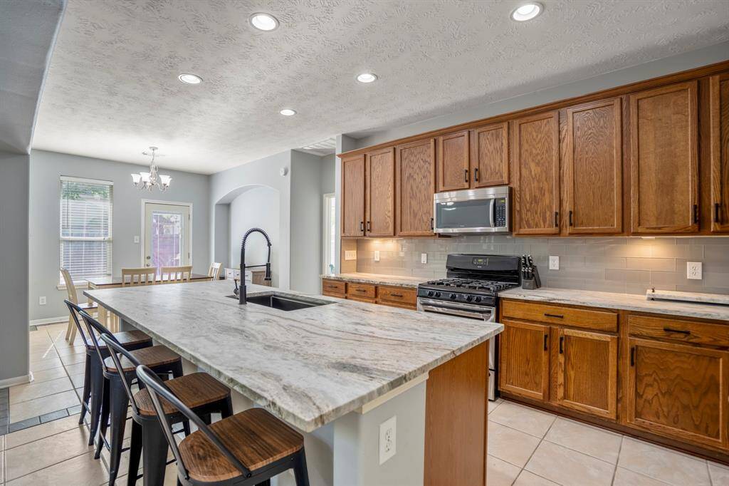 Another angle of the kitchen highlights the striking leathered granite counters and the warm glow of under-cabinet lighting—both functional and stylish touches that elevate the space.