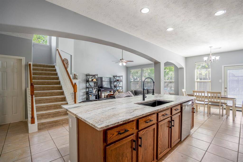 Looking out across the island, you’ll notice generous storage space beneath the countertop, a view of the living room framed by dramatic archways, and the nearby breakfast area. Just to the left of the stairs is the doorway to the half bath, which also leads to a spacious understairs closet.