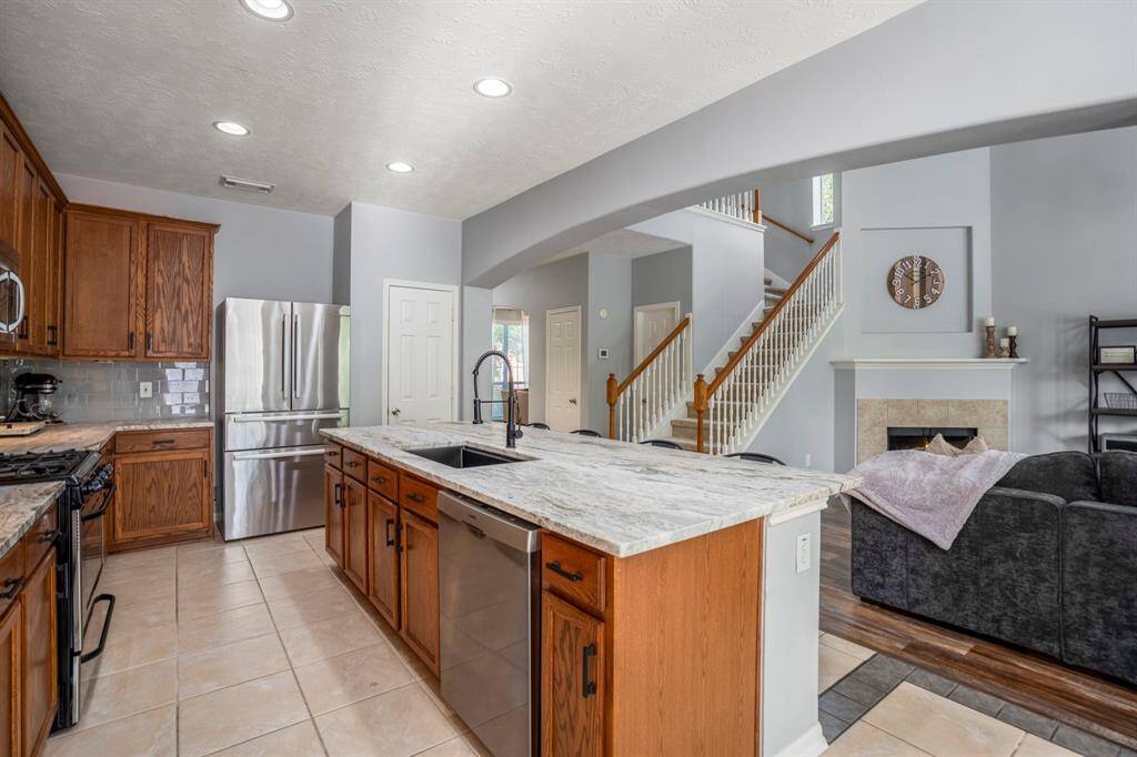 Stepping back toward the breakfast room, this wider view showcases the heart of the home—seamlessly connecting the kitchen, living, and dining areas. The kitchen shines with leathered granite counters, a spacious island with storage, and tall upper cabinets. From here, you can take in the dramatic arched transitions, soaring living room ceilings, and the wall of windows filling the space with natural light.