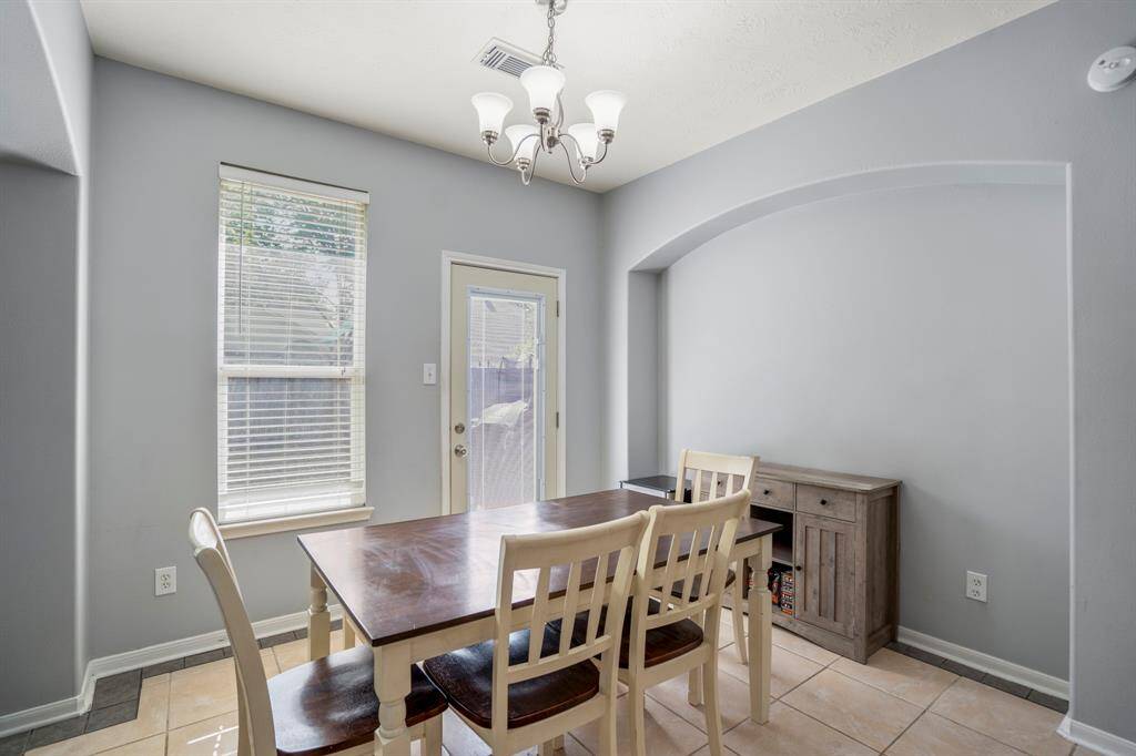 This close-up of the breakfast area showcases a recessed arch that creates the perfect nook for a buffet or display cabinet—adding both style and function without sacrificing space. A large window fills the room with natural light, and the nearby back door offers easy access to the patio for seamless indoor-outdoor living.