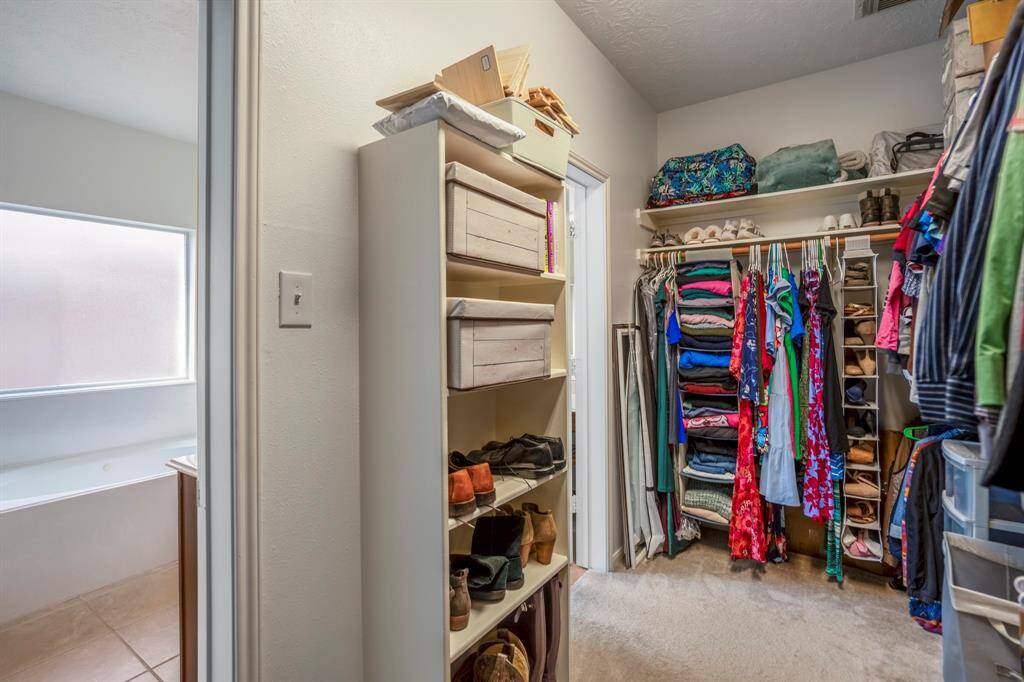 A peek inside the first door reveals the expansive walk-in closet with plenty of hanging space and shelving. The second door leads to the spacious area between the two vanities, offering convenience and privacy in the primary bath layout.