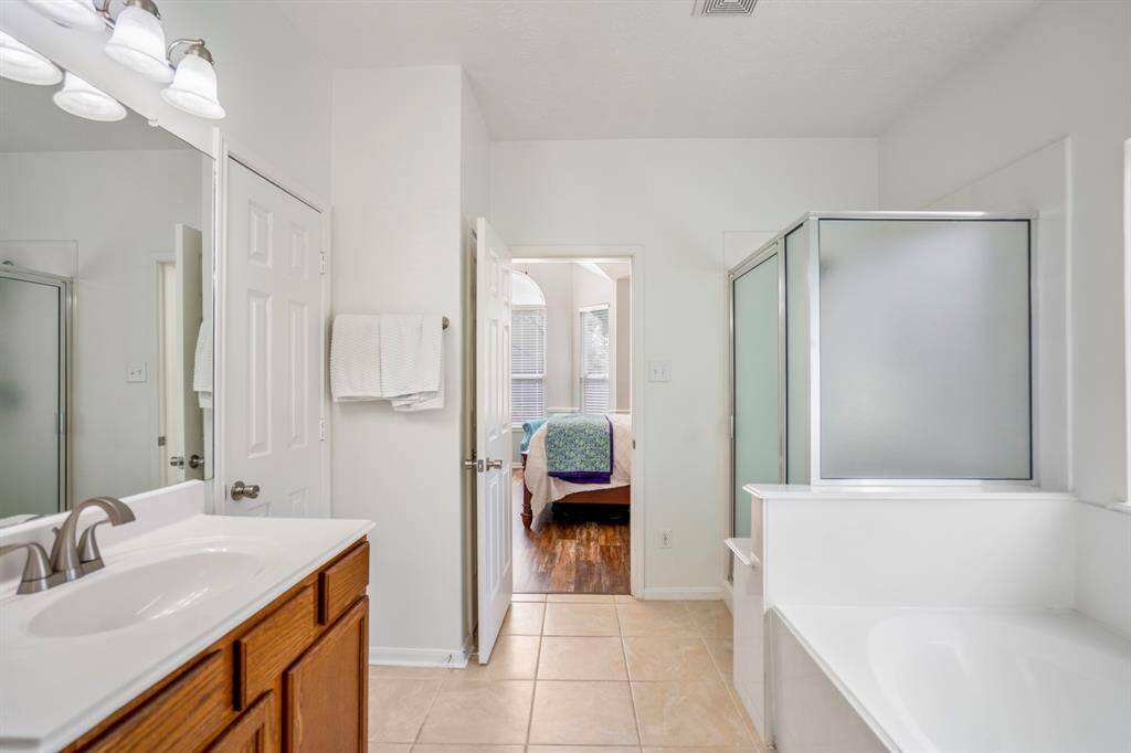 Exiting the second doorway, you get a view back toward the bedroom. The soaking tub and separate shower sit to the right, creating a relaxing retreat just steps from the spacious primary suite.