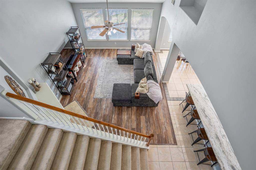 From the upstairs game room, look over the railing for a dramatic view of the living room below, framed by grand vaulted ceilings and large windows. This elevated vantage point also reveals a subtle tile inlay outlining the breakfast area—a stylish detail that defines the space while preserving the home's open-concept flow.