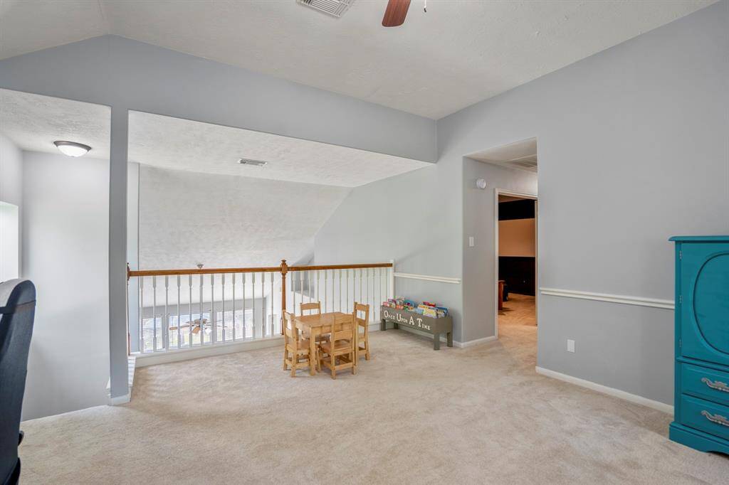 From the game room, we get a great view of the staircase and balcony railing, adding an open, airy feel to the space. Down the hallway to the right, you’ll catch a glimpse of the media room, offering a sneak peek at the entertainment possibilities in this home.