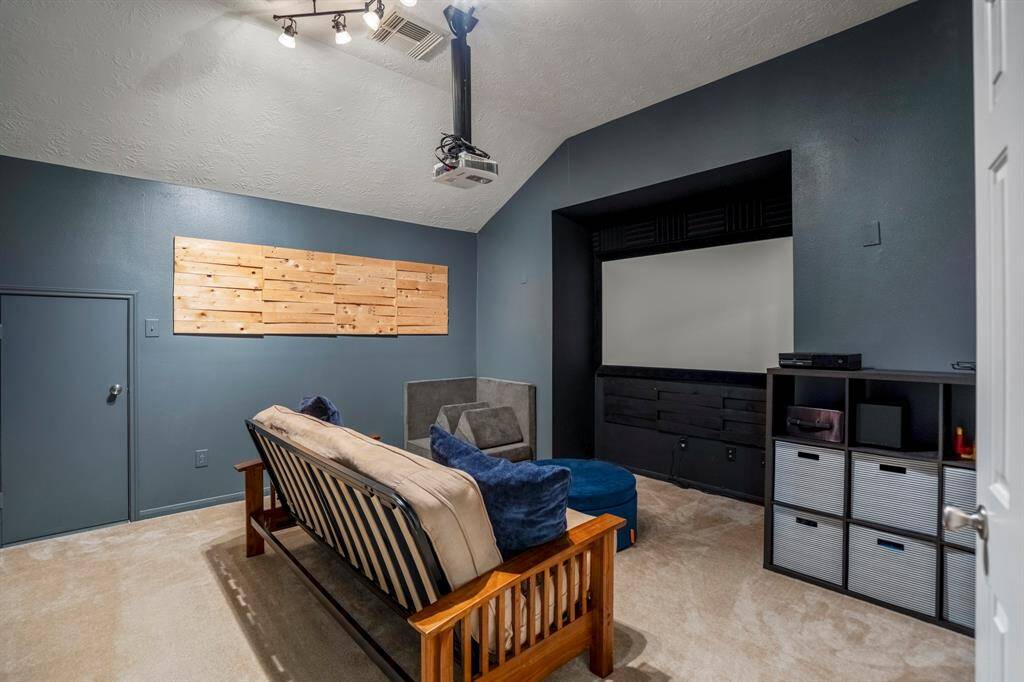 The media room is ready for movie marathons, featuring a unique recessed area perfectly designed for a movie screen, ensuring optimal viewing from every angle. A small door to the left provides convenient access to attic space, adding extra storage or organization options.