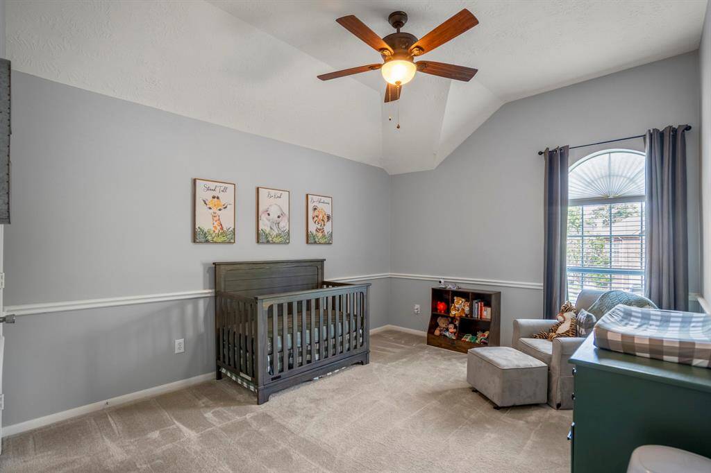 This bright and airy upstairs bedroom boasts a vaulted ceiling, a large window that lets in plenty of natural light, and elegant chair railing. With plenty of space, it’s perfect for creating a cozy retreat or versatile living area.