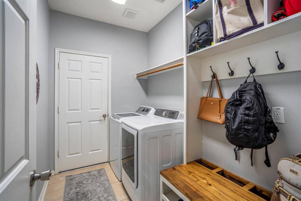 The downstairs laundry room features a custom-built mud bench with hooks and cubby spaces, providing a perfect spot for coats, bags, and shoes. The convenient doorway leads directly to the garage for easy access.