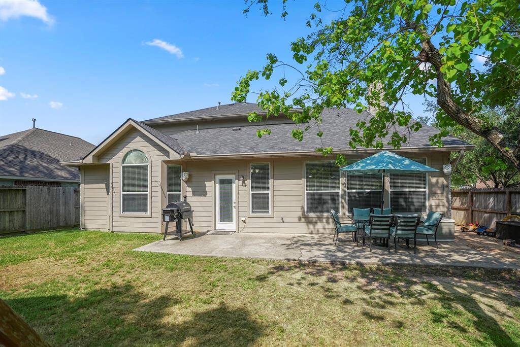 Looking back at the home from near the back fence, you’ll appreciate the spacious yard surrounded by mature shade trees, providing a serene and private setting.