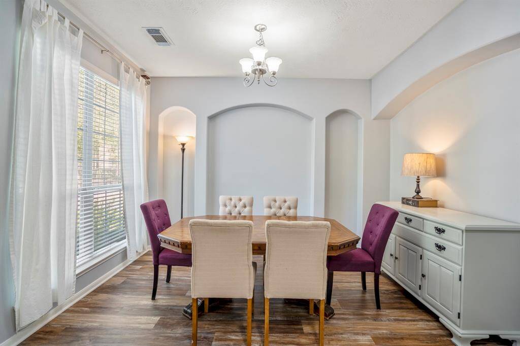 The formal dining room features elegant recessed archways, adding architectural flair to the space. A large window overlooks the front yard, filling the room with natural light and offering a peaceful view.