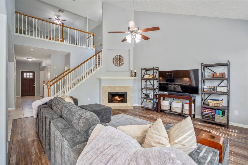 Looking back toward the front entry, this view captures the openness of the layout with a glimpse of the upstairs loft-style game room through the staircase bannister. Just beyond the stairs, a hallway leads to the half bath and a spacious under-stairs closet—perfect for extra storage.