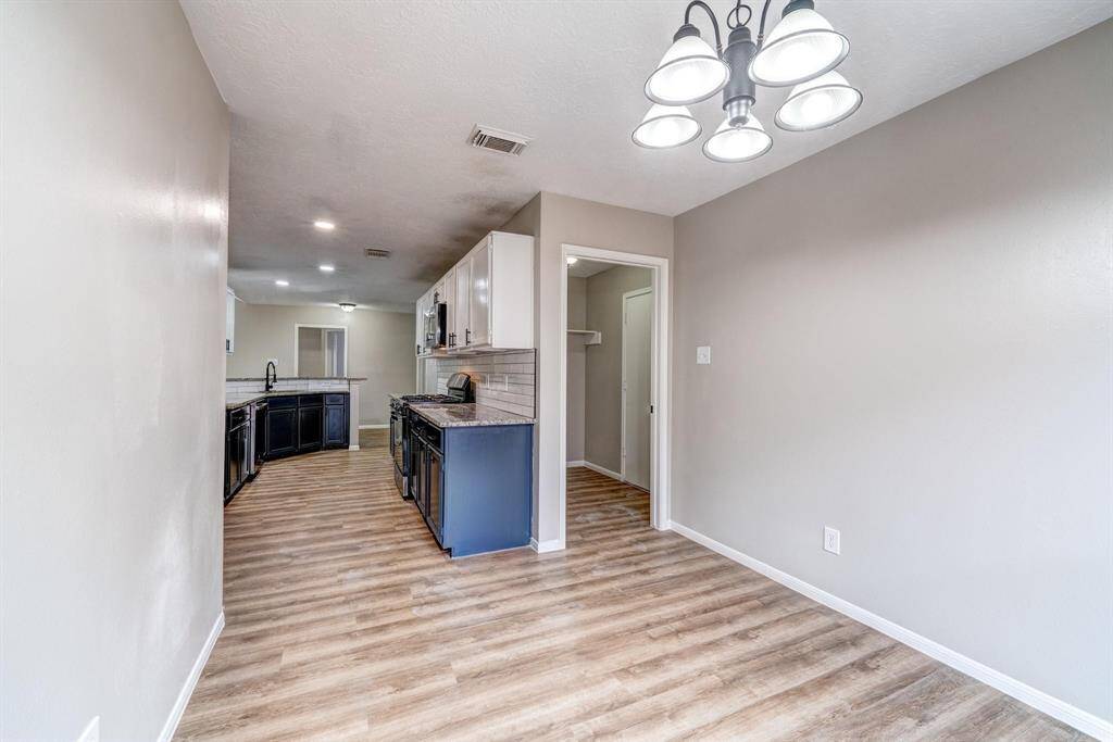 This photo showcases a modern kitchen with sleek cabinetry, stainless steel appliances, and a spacious layout. The adjacent dining area has laminate wood flooring and a stylish overhead light fixture, creating an inviting space for meals and gatherings.