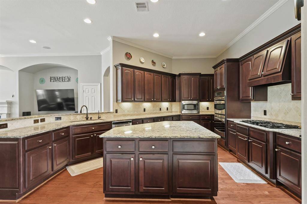 Expansive kitchen layout includes stainless steel appliances, double ovens, and rich wood cabinetry.