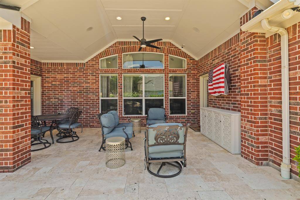 Covered patio with ceiling fan and the multiple seating areas offers a shady retreat for outdoor lounging and dining.