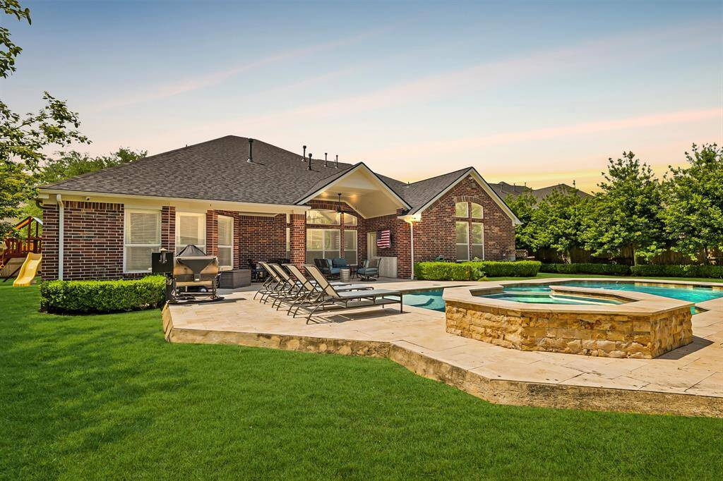 The backyard transforms into a tranquil retreat with glowing pool lights, soft landscaping accents, and a peaceful setting perfect for evening gatherings.
