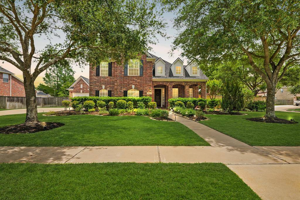 Another angle of the front exterior highlighting the lush lawn and shade from mature trees.