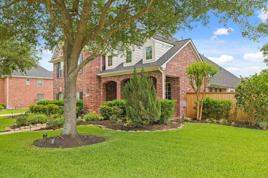 Side view of the home showcasing privacy fencing, green space, and full-brick exterior.
