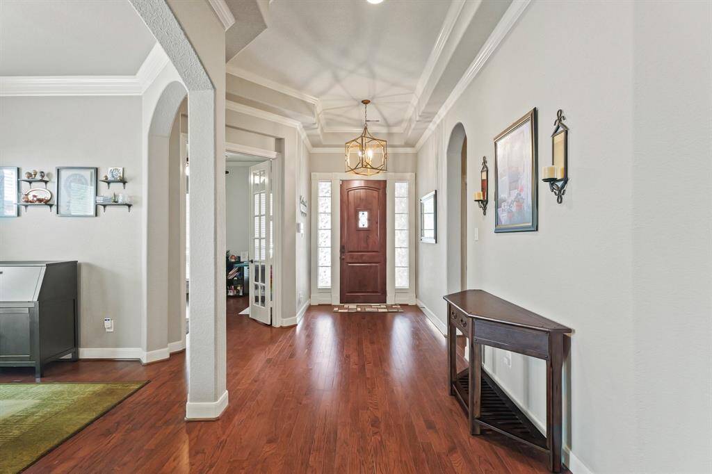 Bright and inviting foyer with tall ceilings, crown molding, and wood flooring that flows throughout the main living areas.