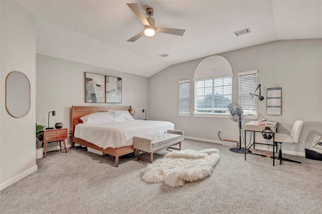 The spacious primary bedroom features a carpeted floor, ceiling fan, and air vents for optimal comfort.