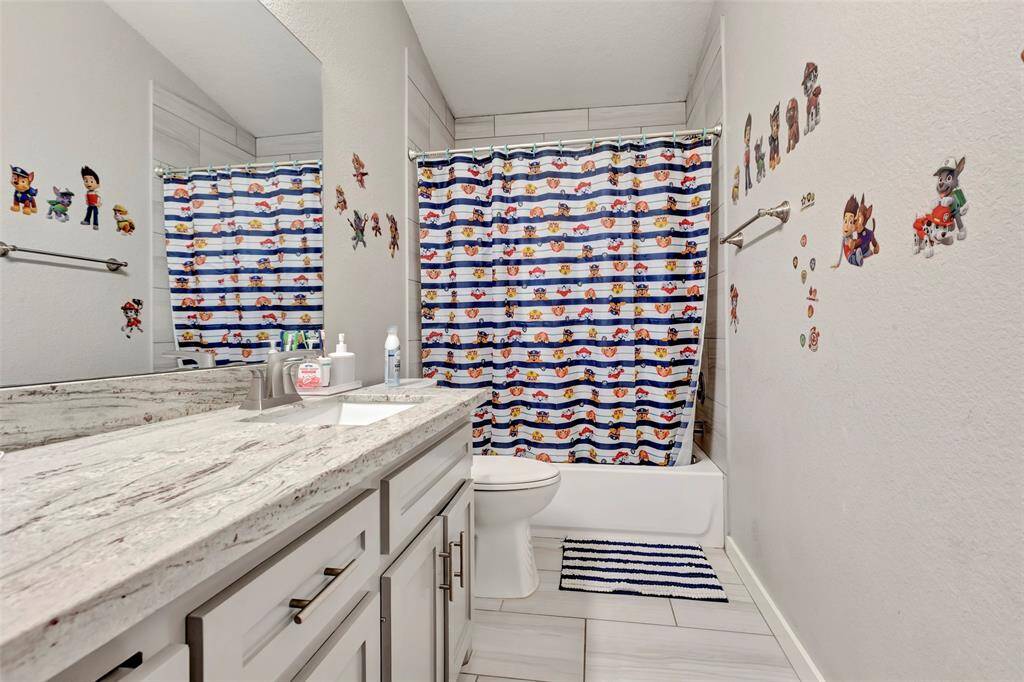 Another secondary bathroom upstairs, equipped with a shower, toilet, and granite countertop.