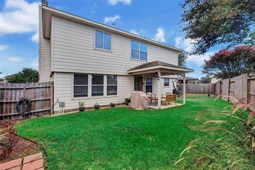 Rear view of the home showcasing a covered patio and a fenced backyard.