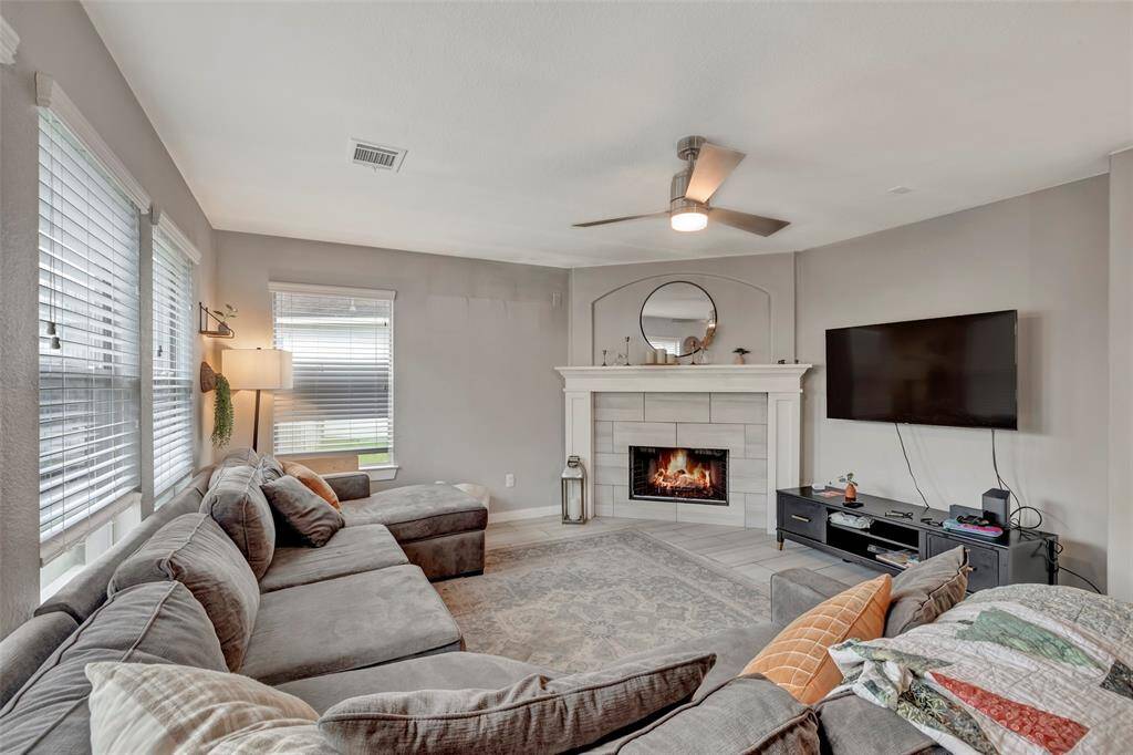 It has a cozy living room featuring a gas-connected fireplace and a ceiling fan.