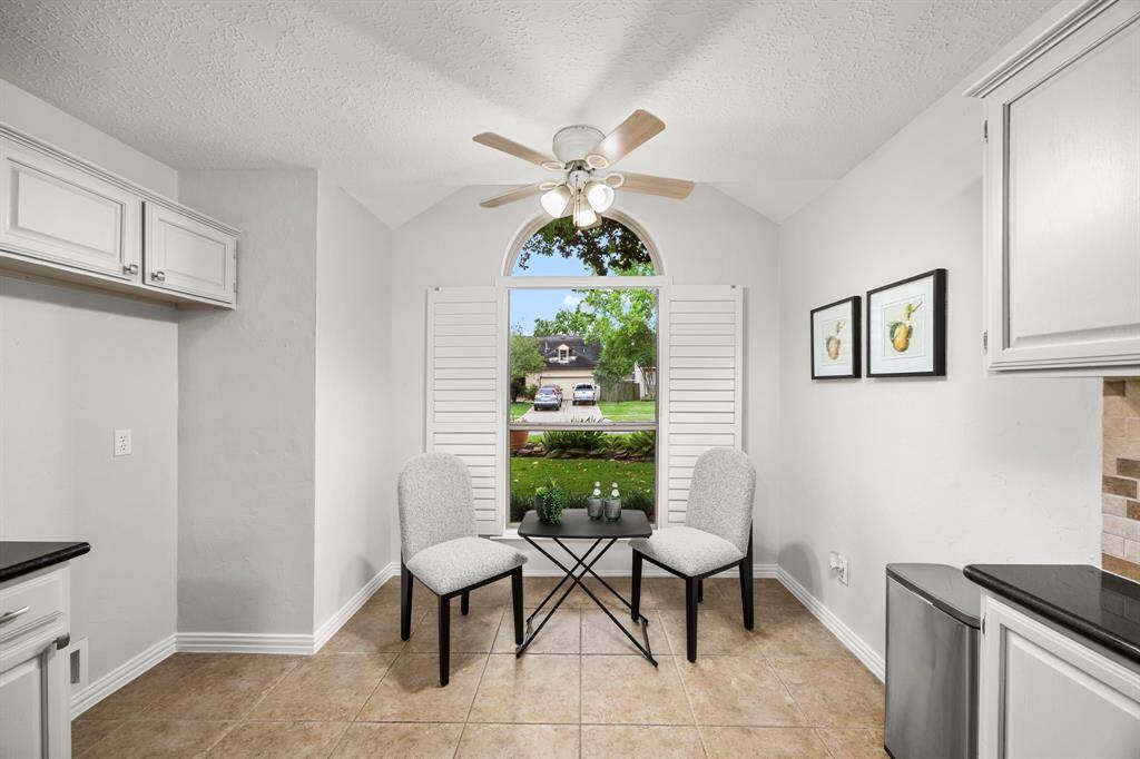 Bright breakfast nook with tile flooring, featuring a large window with shutters, providing plenty of natural light.
